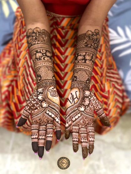 A beautiful and intricate engagement henna design. The palms feature the couple's initials, V and H, hidden within classic heart shapes, making the design both traditional and deeply personal.