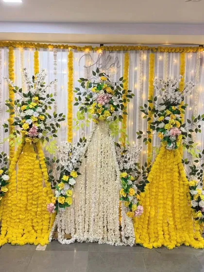 This backdrop for a Haldi or Mehandi ceremony uses curtains of yellow and white flowers. The design creates a beautiful floral wall effect, perfect for elegant and fragrant celebrations.