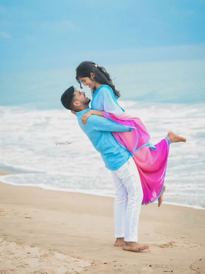The beach provides a perfect canvas for romantic and playful couple portraits. This destination shoot captures a classic lift against the backdrop of the waves and open sky.