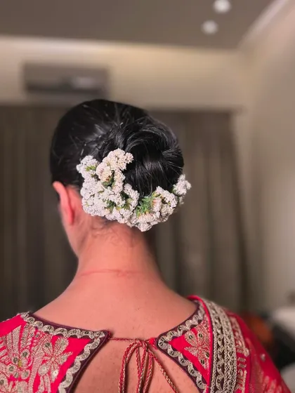 A classic, clean bridal bun adorned with a simple gajra of white flowers. This timeless look is the epitome of grace and elegance for a wedding ceremony.