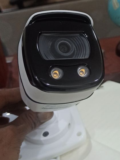 A handheld view of a full-color bullet camera with two built-in warm lights. These lights activate in darkness to enable clear, colorful night vision.