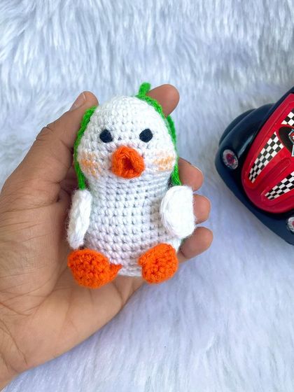 A cute little duck car hanging. With his green cap and cheerful expression, he's sure to bring a smile to your face on every drive.