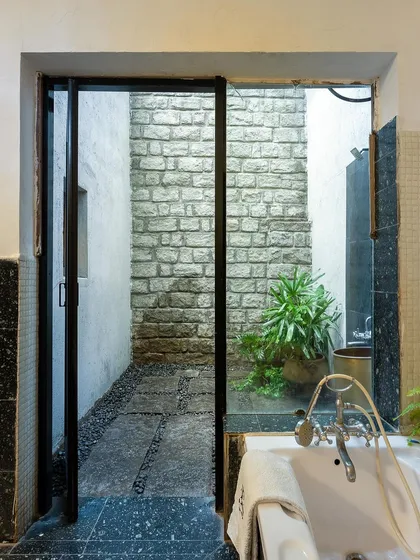 Another view of the open-sky bathroom, showing the seamless connection between the indoor space and the natural elements outside.