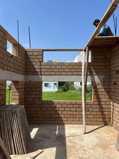 A view from inside a room under construction, with the mud block walls rising. The openings for windows are framed, offering a first glimpse of the views that the finished home will have.