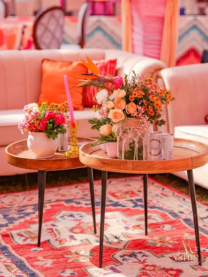 A close-up of the lounge area's coffee tables, styled with fresh flowers and chilled drinks, set on a beautiful patterned rug.