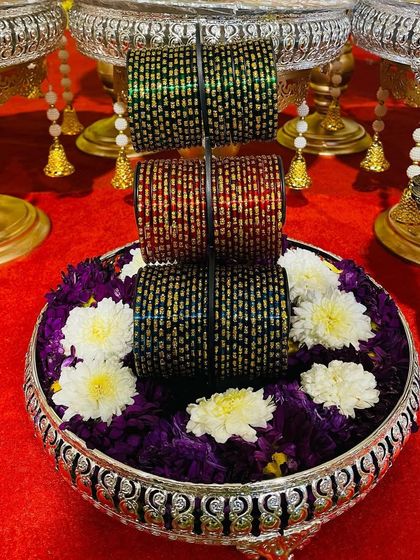 A traditional bangle display for a Seemantham or baby shower. The colorful glass bangles are beautifully arranged on a silver plate with fresh flowers, symbolizing blessings for the mother-to-be.