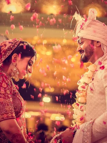 A beautiful, emotional moment between the couple during the varmala exchange, surrounded by a shower of petals.