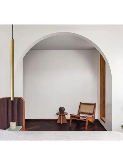 This master bedroom features a custom bed with a soft, upholstered headboard. The design is framed by an archway, creating a cozy, cocoon-like feeling for the sleeping area.