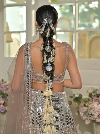 A detailed back view of a contemporary bubble braid adorned with metallic, coin-like charms and tassels. This hairstyle was designed for a modern bridal campaign, blending tradition with edgy accessories.