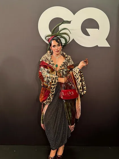The full avant-garde look for the GQ event. The elaborate hairstyle, with its sculpted waves and green feather headpiece, was the centerpiece of this creative ensemble.