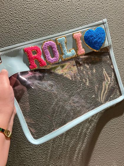 A beautiful light blue clear pouch, personalised with a name and a fuzzy heart patch. It's a sweet and stylish way to stay organised.