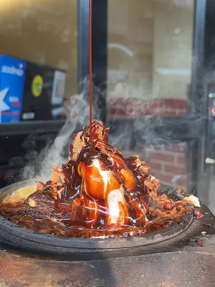 A close-up of my Sizzling Brownie with Ice Cream, with chocolate sauce being drizzled on top. It's a feast for the senses.