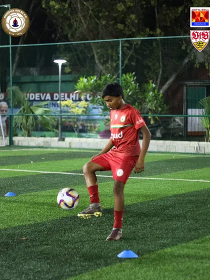 A young player with his foot on the ball, ready for the next move. We teach our players to be comfortable and confident in possession.