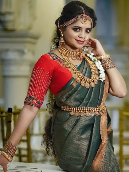 A model wearing our Kasu Mala set with a dark green saree. The contrast makes the gold jewellery pop, creating a striking look.