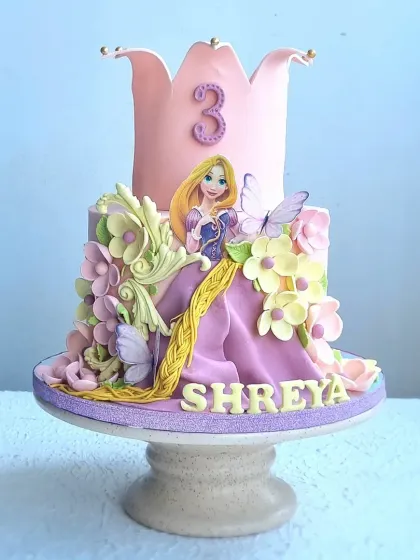 This Rapunzel cake features a large, sculpted crown tier and a bas-relief effect for Rapunzel's dress and hair. I'll show you how to create these 3D elements and arrange sugar flowers to complete the magical look.