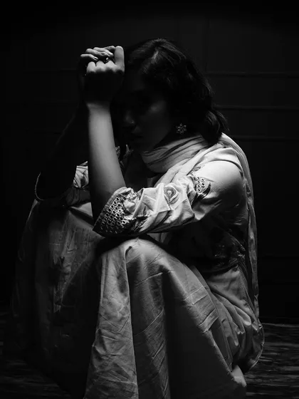 A poignant black and white image where the model is seated in darkness, her form illuminated by a soft light. The pose suggests introspection and emotion, showcasing my ability to capture mood.