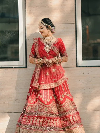 A classic portrait of the bride, looking radiant in the sunlight which highlights the beautiful mirror work on her red lehenga.