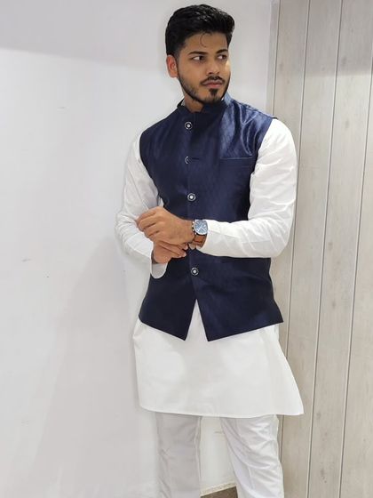 A relaxed pose in the navy blue jacquard jacket and white kurta, perfect for a sangeet or engagement party.