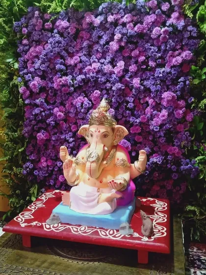 A simple yet powerful backdrop made of a dense wall of purple flowers. This minimalist design makes the Ganpati idol stand out beautifully.