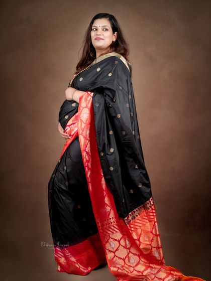 A stunning portrait in a black and red silk saree. The rich colors and textures of the fabric create a luxurious and regal feel.