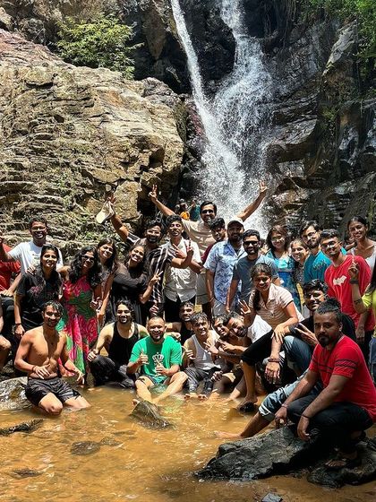 A happy group enjoying a refreshing break at a waterfall during our Kudremukha region trek.