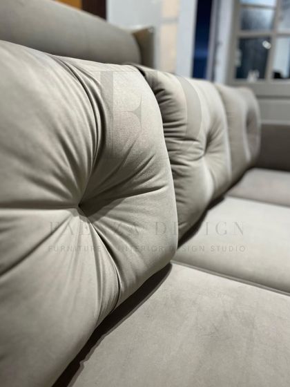 This three-seater sofa in a neutral beige features deep, tufted back cushions for added comfort. Its clean lines and simple form make it a versatile foundation for any living room design.