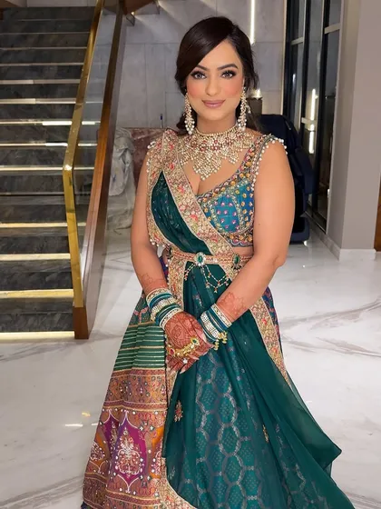 The full look. The rich green and blue tones of her outfit are complemented by the soft, glowing makeup.