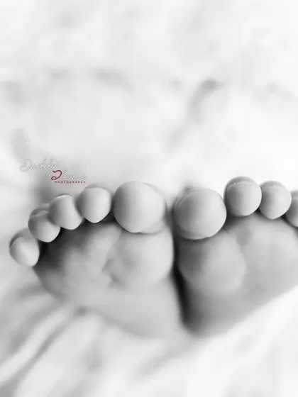 A beautiful black and white close up of a newborn's toes. This artistic shot emphasizes the texture and shape of their tiny feet.