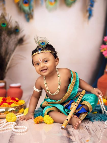 A joyful portrait of a baby boy dressed as Little Krishna, complete with a flute, peacock feather, and a charming smile.