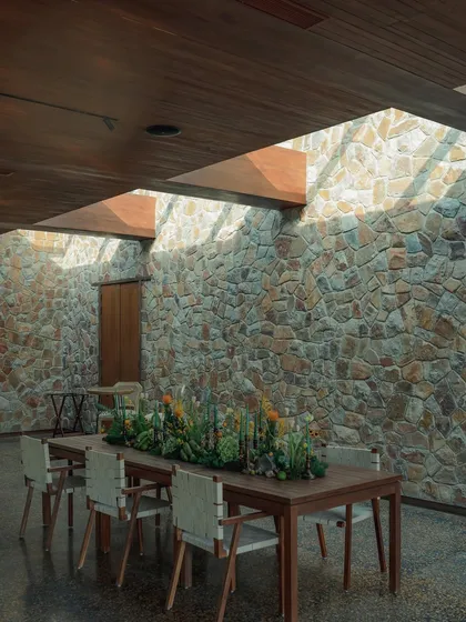 Our indoor dining room offers a different kind of intimacy. The warmth of the wooden ceiling and the rustic texture of the stone wall create a timeless backdrop for private dinners and special gatherings, illuminated by natural light from the skylights.