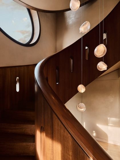A close-up of the custom wooden handrail and the delicate, hand-blown glass pendants. This image emphasizes the level of craftsmanship and material detail that we bring to our projects.