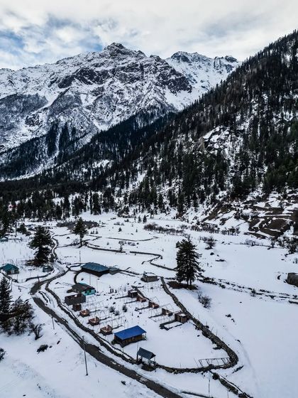 An aerial shot of a campsite in the snow in Kinnaur, showing the contrast between the wild landscape and human settlement.