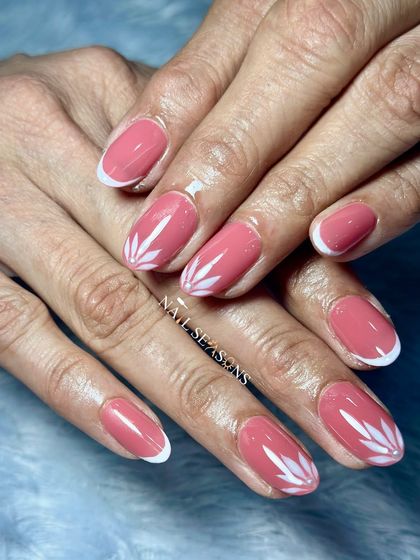 A fresh, clean, and classy look with soft pink nails, white French tips, and delicate white leaf accents.