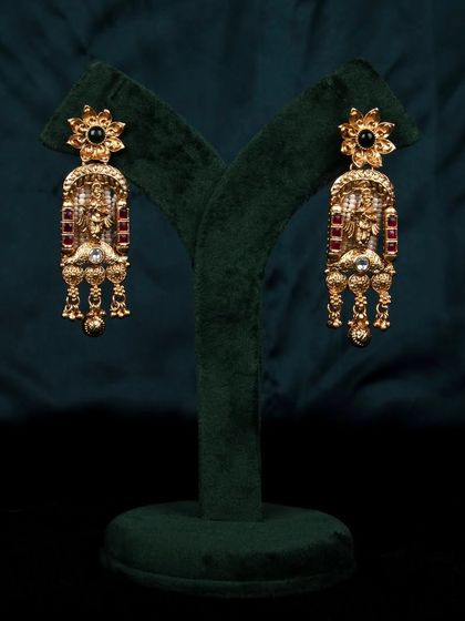 The intricate gold earrings displayed on a green stand, providing a clear and unobstructed view for e-commerce listings.