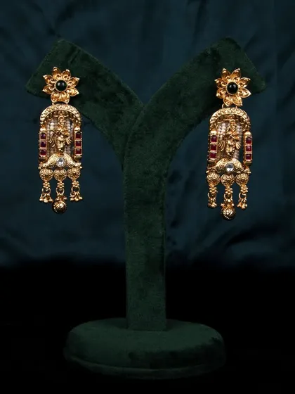 The intricate gold earrings displayed on a green stand, providing a clear and unobstructed view for e-commerce listings.