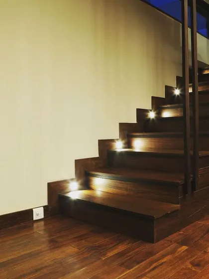 The illuminated staircase at night creates a dramatic and welcoming effect.