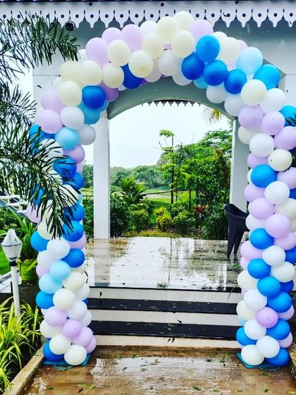 A large balloon arch at the entrance of an outdoor birthday party venue, welcoming guests to the celebration.