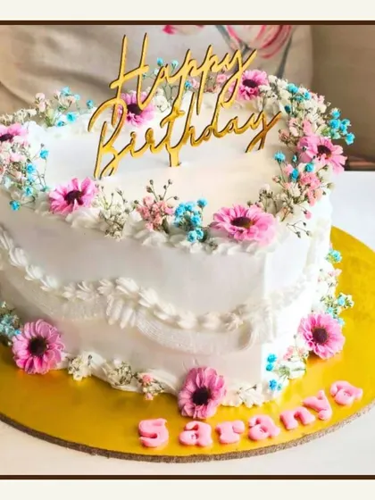 A lovely heart-shaped cake decorated with a border of fresh, delicate pink and blue baby's breath flowers.