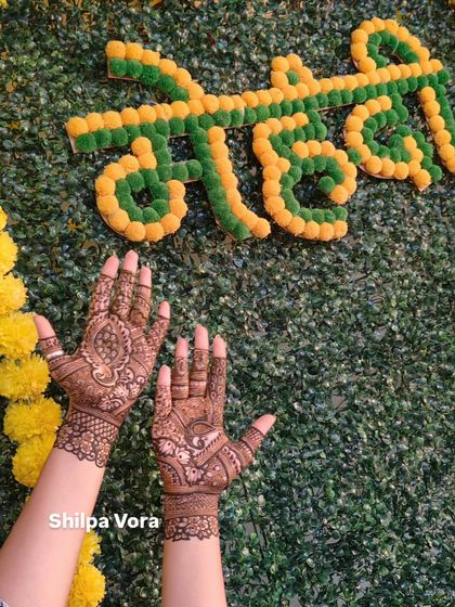 A simple and elegant design shown against a festive 'Mehndi' backdrop, ideal for guests at a wedding or party.