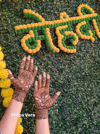 A simple and elegant design shown against a festive 'Mehndi' backdrop, ideal for guests at a wedding or party.