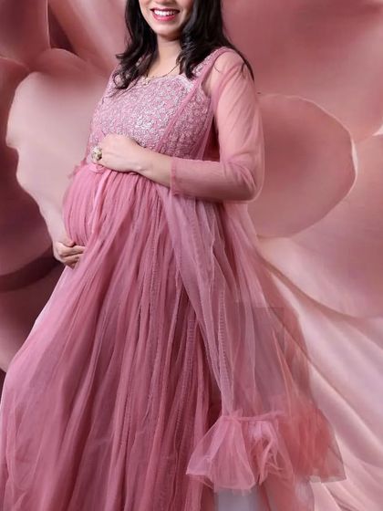A pastel pink jacket-style maternity gown that offers a unique and elegant silhouette. The sheer jacket adds a layer of sophistication to the look.