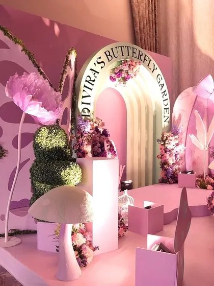 Another view of the "Divira's Butterfly Garden" setup, showcasing the different levels and props like giant mushrooms and oversized flowers that create a whimsical landscape.