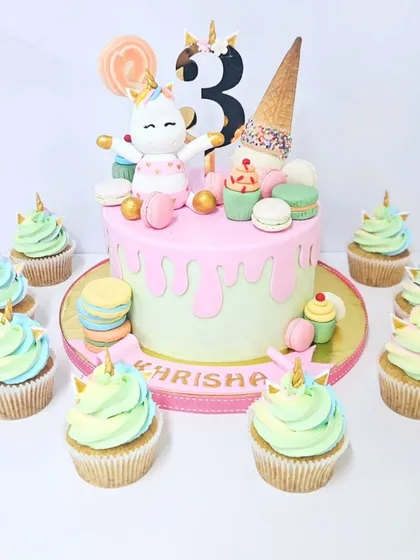 This unicorn-themed cake is pure sweetness, complete with a drip effect, macarons, and an adorable unicorn topper. The matching unicorn cupcakes make it a perfect party set for a third birthday celebration.