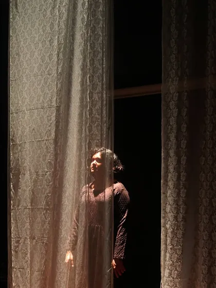 A daughter yearns for the outside world in "The House of Bernarda Alba." The set and lighting design create a feeling of confinement, with light representing a hope for freedom.