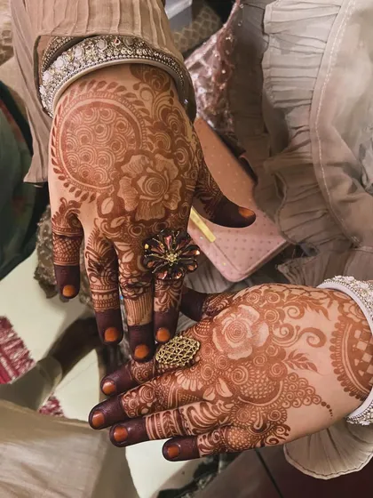 A close-up of the beautiful henna stain, adorned with rings. Our designs complement your festive look perfectly.