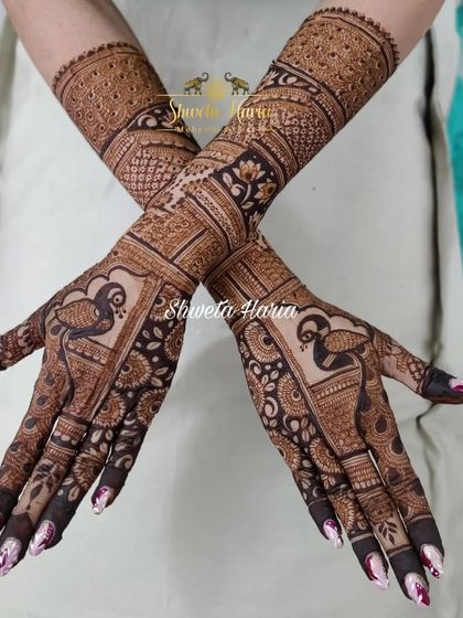 A crossed-arm view of the bridesmaid's mehendi, highlighting the flow and complexity of the traditional peacock patterns.