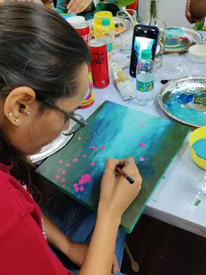 A close-up of a participant adding final touches to her abstract painting during the AIIMS doctors' workshop.