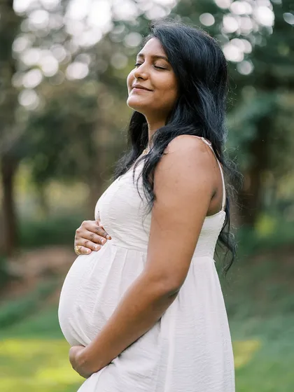 A moment of pure bliss. The mother-to-be soaks in the warmth of the sun in a beautiful park setting. This image captures the feeling of peace and gratitude during pregnancy.