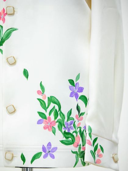 A close-up of the delicate floral work on the white Lachka suit. Painting flowers is one of my favorite things to do; I love how they bring a sense of life and grace to the fabric.