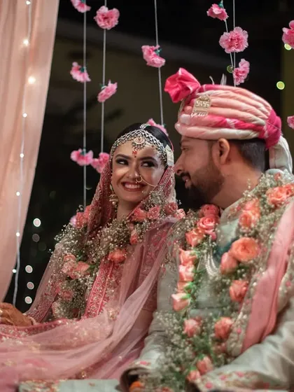 A quiet, candid moment between the couple at their mandap, surrounded by pink floral decor.